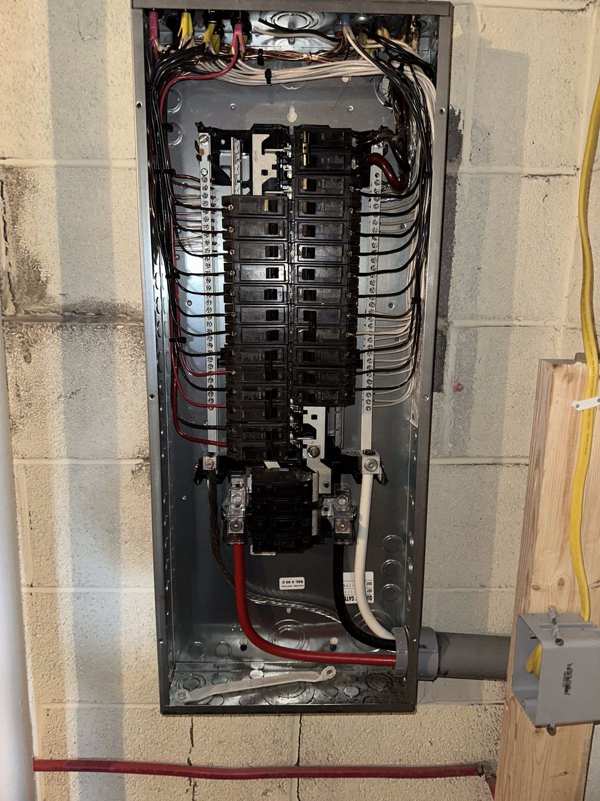 Upgraded breaker panel on a basement block wall with new service conductors